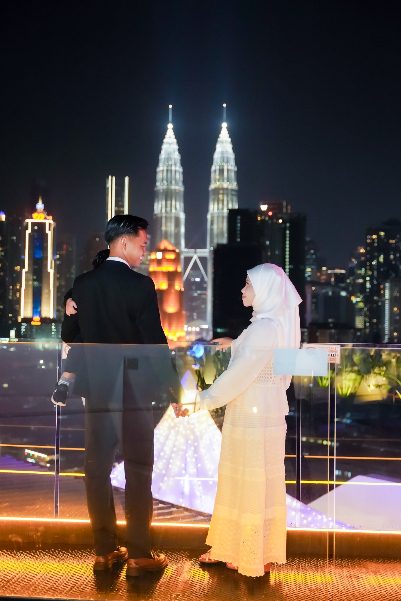 Momen pasangan berpegangan tangan dengan pemandangan KLCC