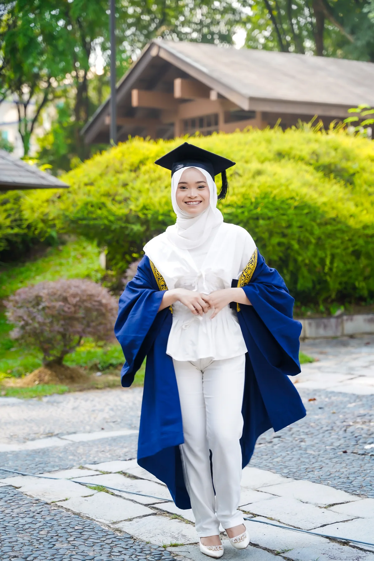 Potret graduan berjubah biru di taman