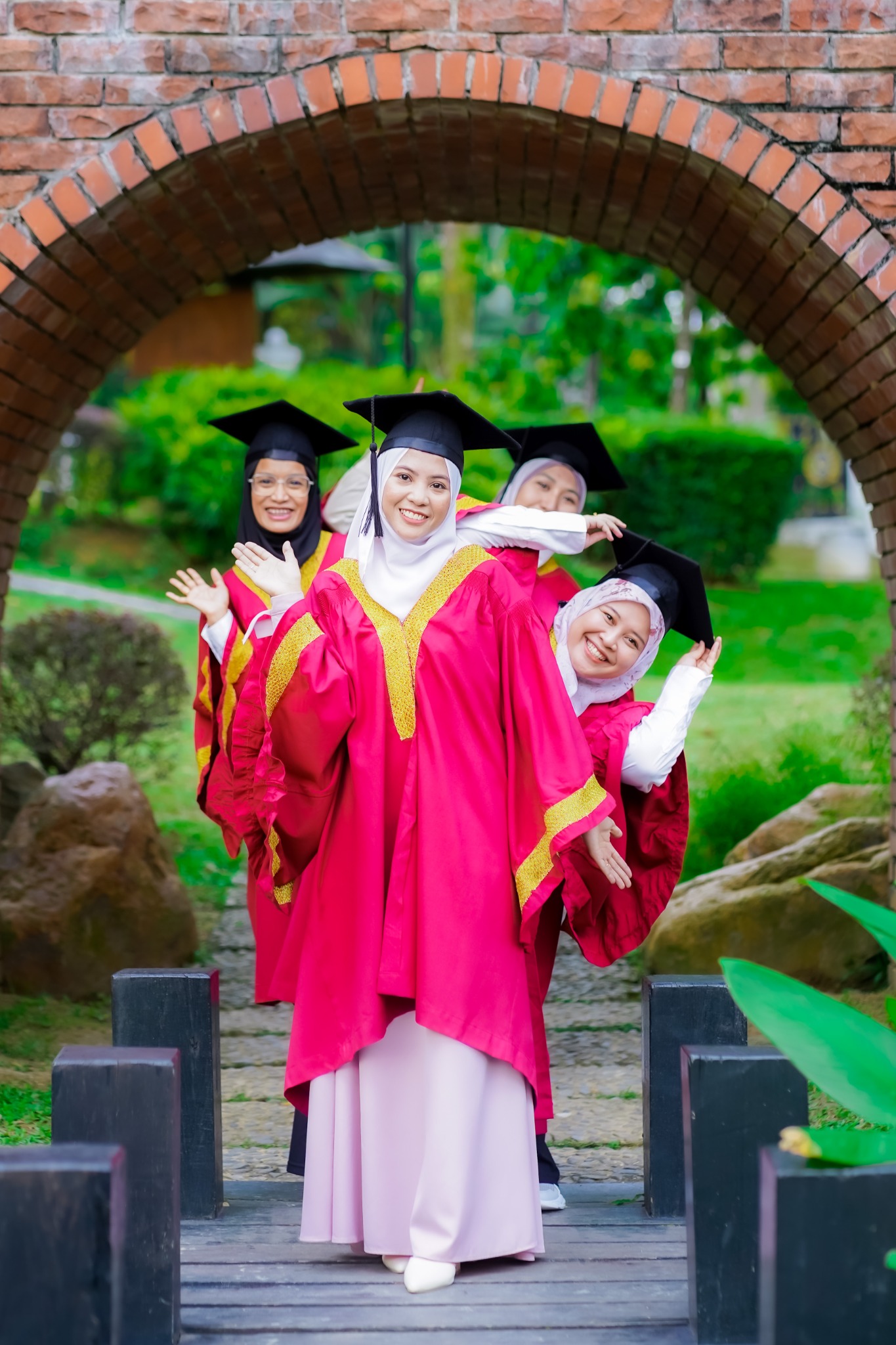 Empat rakan mengintai dan bergaya ceria di bawah gerbang bata semasa sesi Pre Convo.